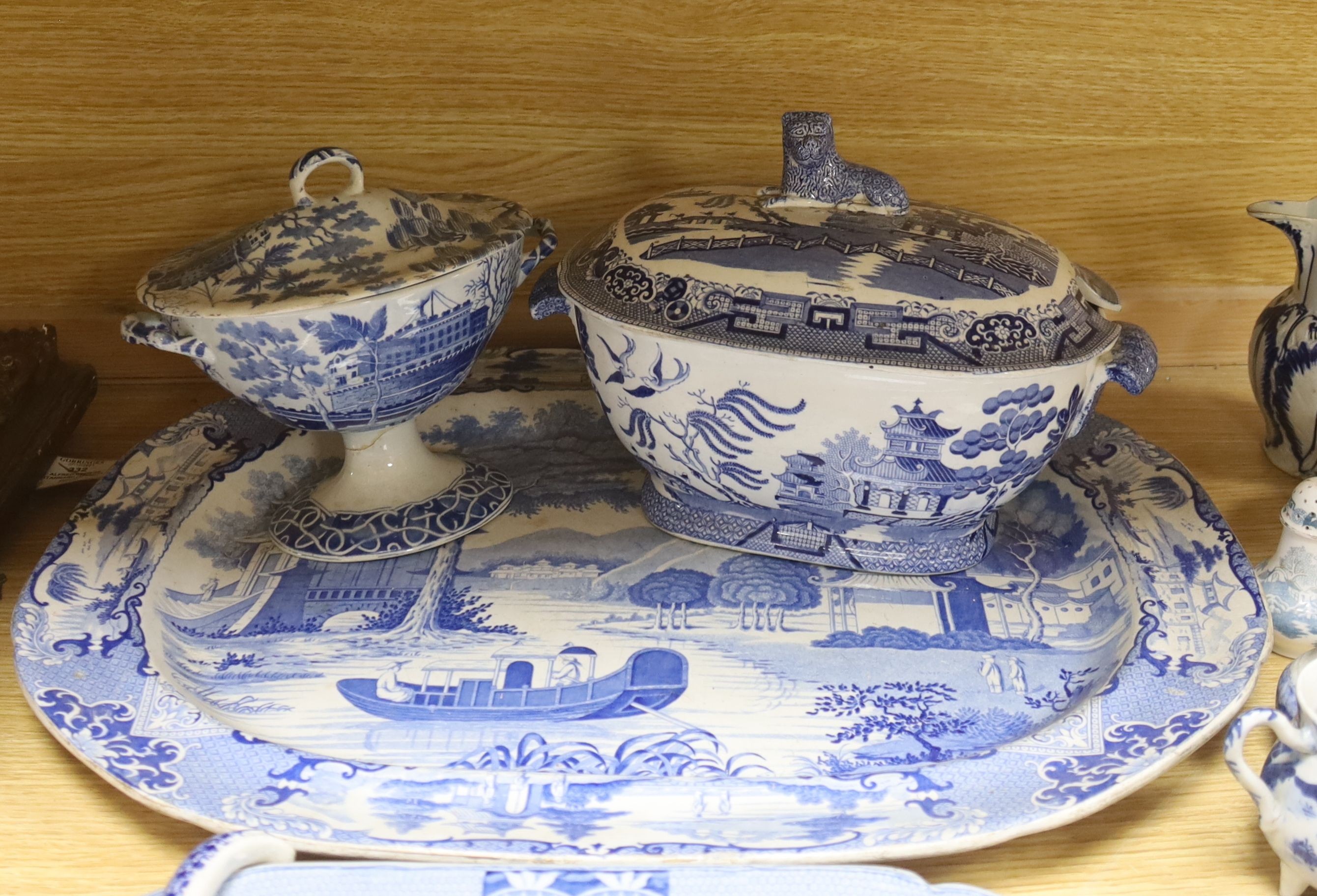 A group of 19th century blue and white pottery to include a chinoiserie pattern meat plate, 53.5 cm, a patent ironstone pheasant pattern dish, 47.5 cm, various tureens, dishes, ladles etc. a pearlware jug and two Chinese